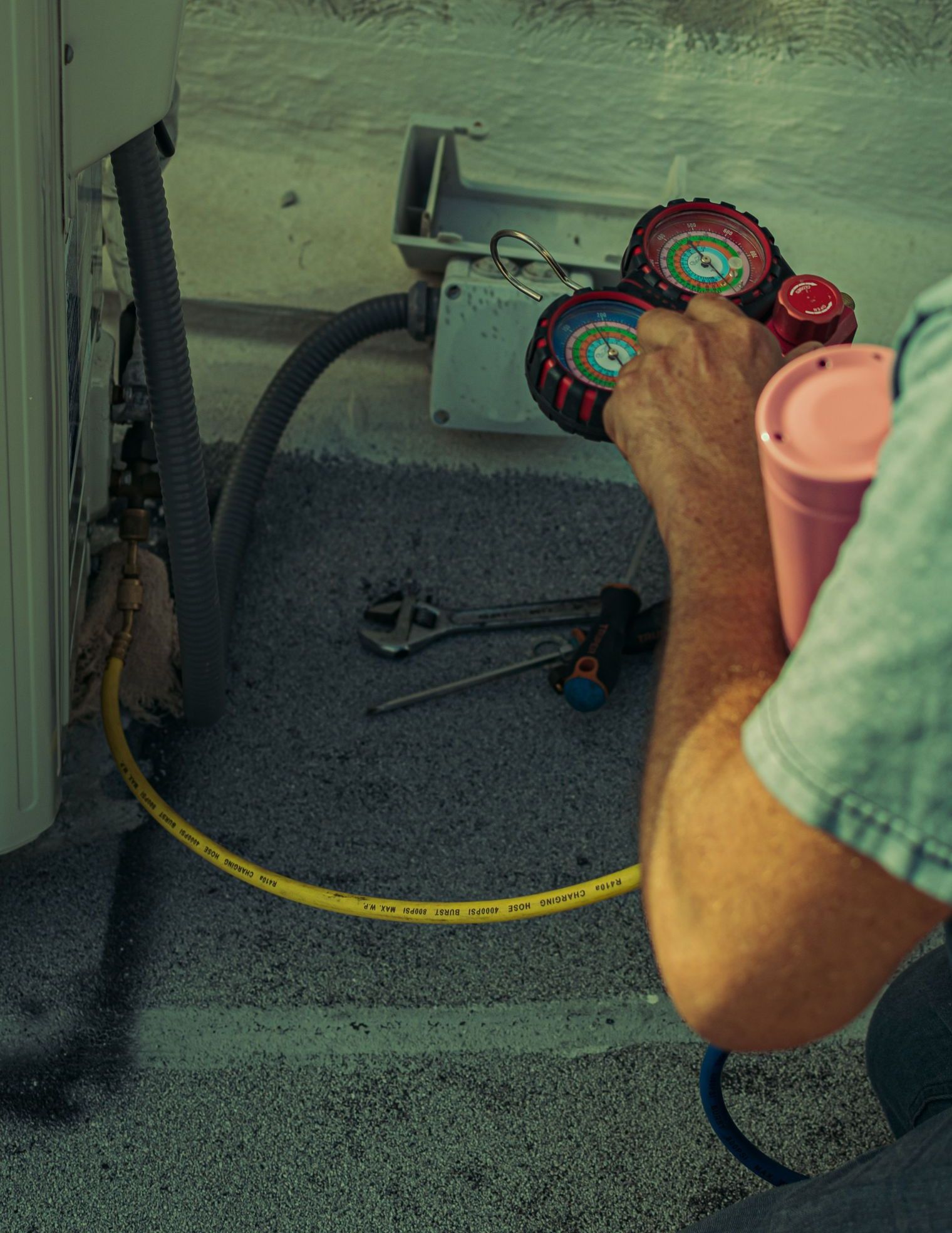 A technician checks and repairs an HVAC system outdoors using tools and gauges.